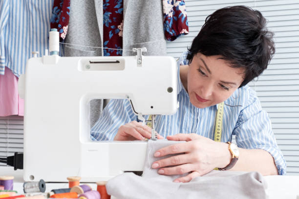 istock Seamstress working at tailor shop with electrical industrial sewing machine 1134983331