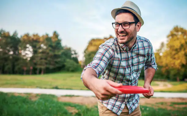 Man have fun with flying disc in the park. Sport and recreation concept