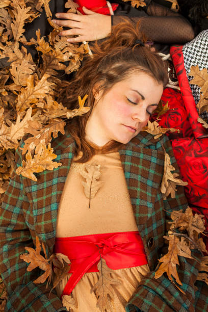 Sleeping woman lied down in floor full of leaves. Woods in Autumn stock photo