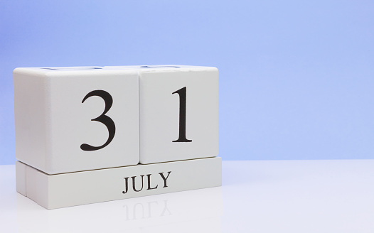 July 31st. Day 31 of month, daily calendar on white table with reflection, with light blue background. Summer time, empty space for text