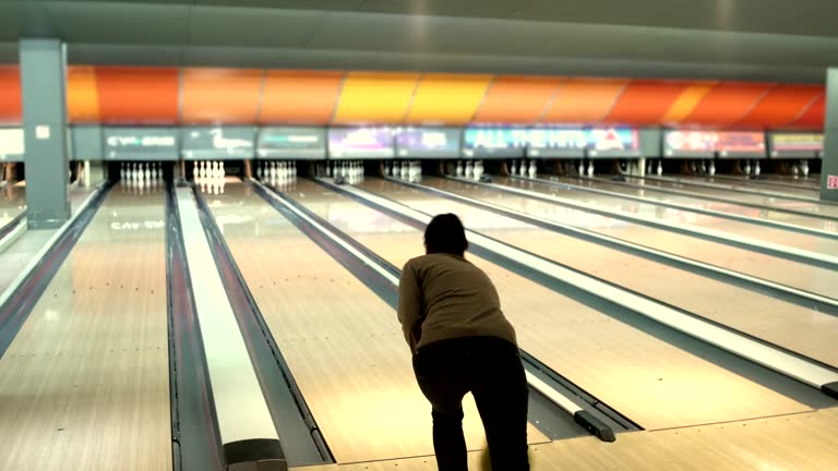 Middle aged woman clumsy throwing ball in bowling club