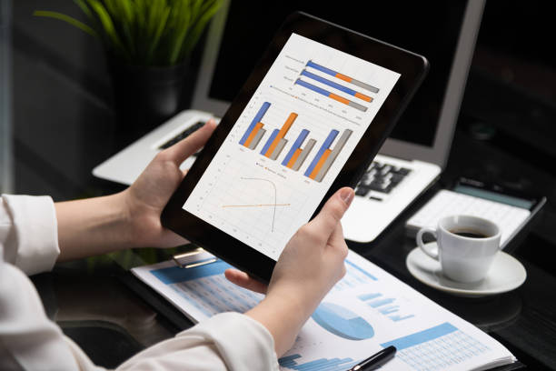 istock Close-up hands holding tablet on background of financial documents 1134997152