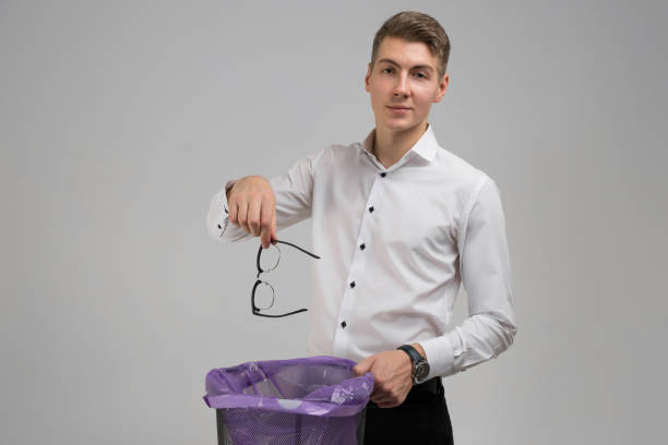 istock Young man throws glasses in trash isolated on white background 1134997196