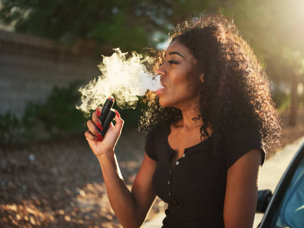 femme afro-américaine vaping et exhalant nuage de fumée - puffed photos et images de collection