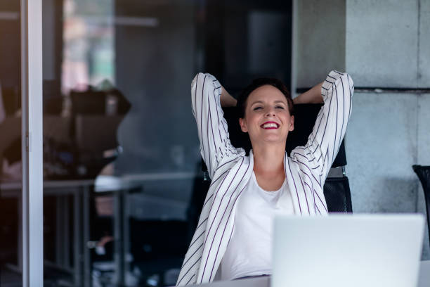 istock Relaxing at working place. Attractive young woman holding hands behind head and keeping eyes closed while sitting at her working place 1135007713