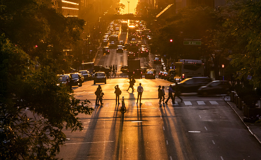 People standing in the intersection of 42nd Street and Second Avenue watching the sunset between the buildings of Midtown Manhattan in New York City