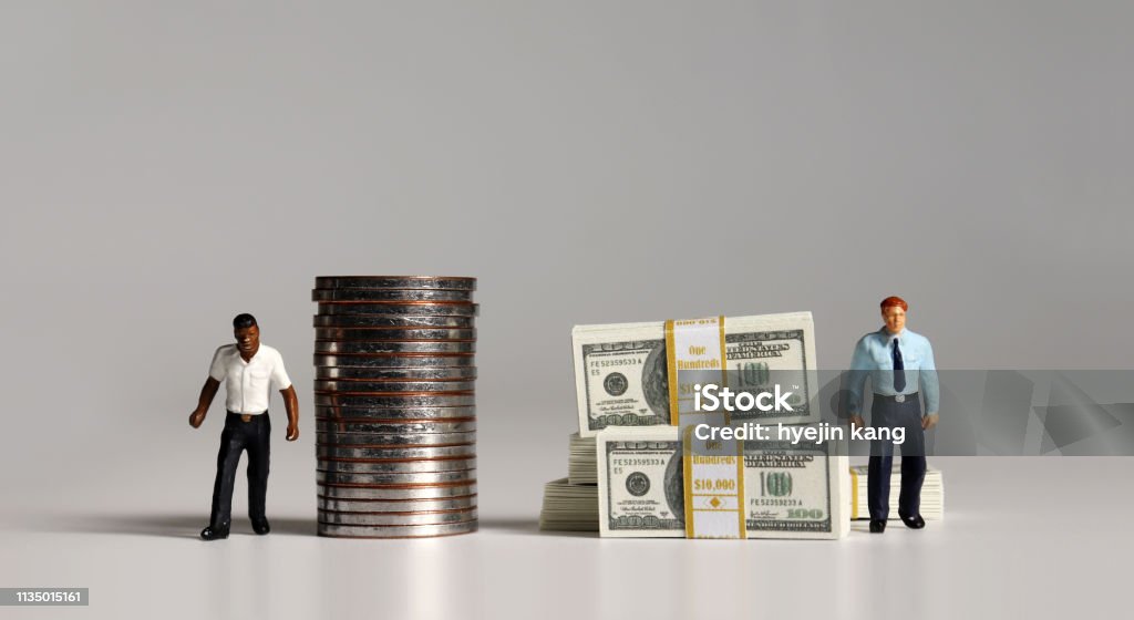 A pile of bills and coins. Miniature people. The concept of racial and income disparity. Imbalance Stock Photo