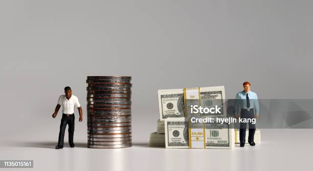 A Pile Of Bills And Coins Miniature People The Concept Of Racial And Income Disparity Stock Photo - Download Image Now