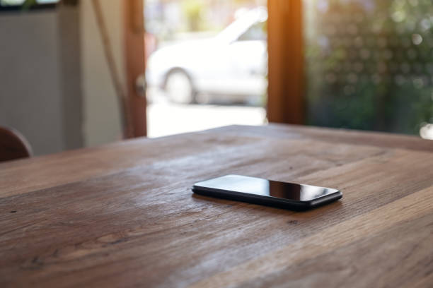 木製のテーブルの上の単一の携帯電話 - copy space left ストックフォトと画像