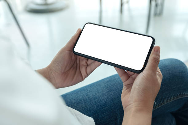 istock Mockup image of woman's hands holding black mobile phone with blank white screen horizontally in cafe 1135024046