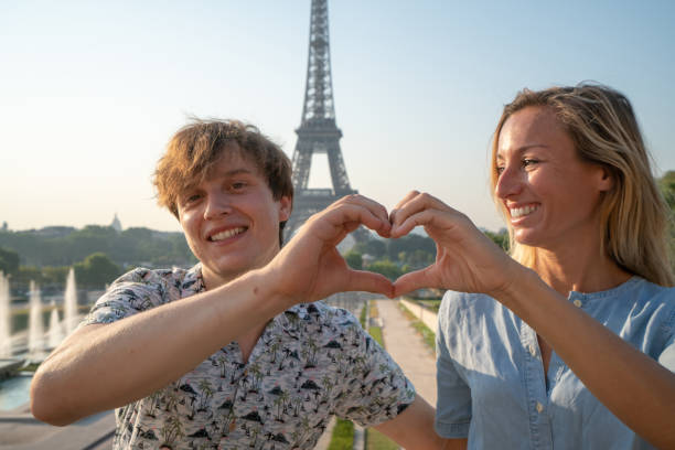 istock Young couple making heart shape finger frame with hands against the Eiffel Tower in Paris 1135024487