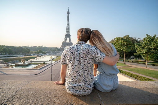 Young couple at the Eiffel Tower in Paris contemplation the urban skyline People travel discovery city concept\nYoung caucasian woman tourist in Paris