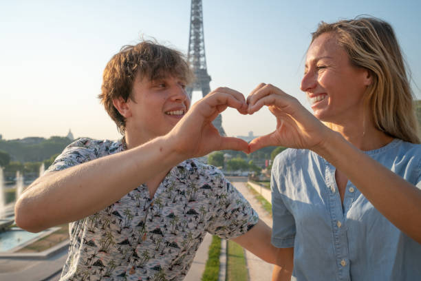 istock Young couple making heart shape finger frame with hands against the Eiffel Tower in Paris 1135025918