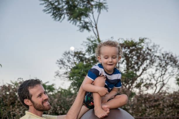 istock Father holding son high on top of slide 1135027755