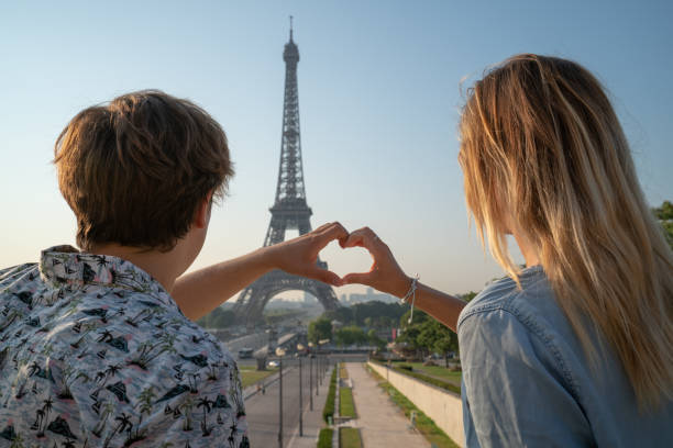 istock Young couple making heart shape finger frame with hands against the Eiffel Tower in Paris 1135029341