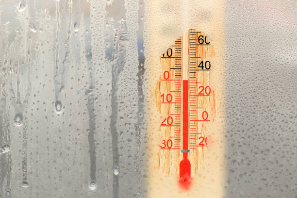 das thermometer im freien zeigt im wintertag 0 grad celsius. äußeres thermometer an einem gefrorenen fenster - subtraktion grafiken stock-fotos und bilder