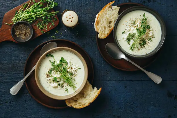 Creamy caulflower and broccoli with feta soup on dark blue background