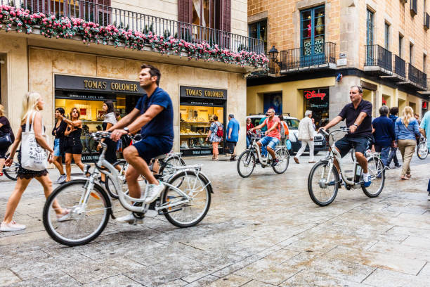Barcelona, Spain - 4th October 2017: A tourist group on bicycles cycles down a pedestrianised shopping street. The city receives millions of tourists every year.
