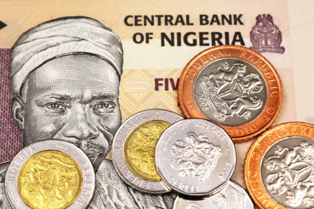 A macro image of miscellaneous Nigerain coins on a five Naira bank note from Nigeria