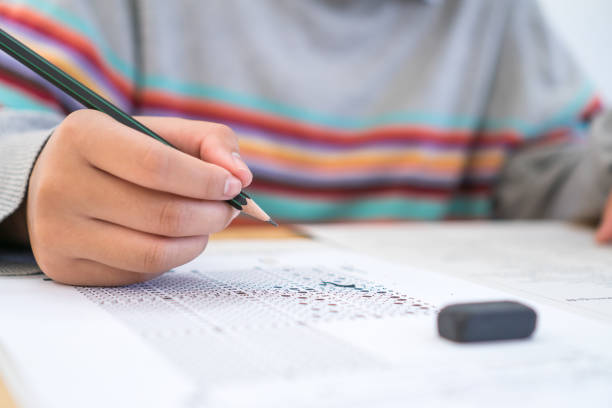 istock Exams test student in high school, university student holding pencil for testing exam writing answer sheet and exercise for taking in assessment paper on wood table classroom. Education study Concept 1135034051