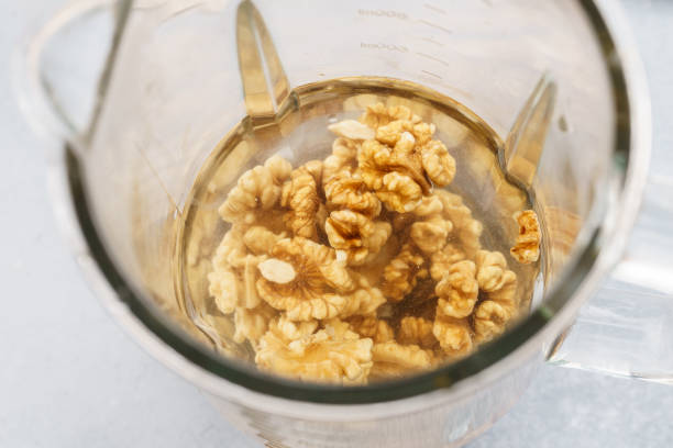 licuadora y nueces empapadas en agua. haciendo leche vegana. - nuez fotografías e imágenes de stock