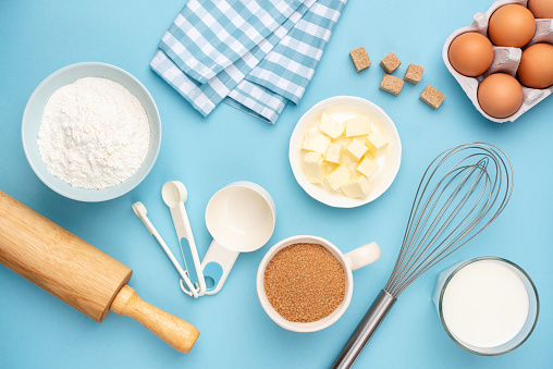 Kitchen utensils and baking ingredients on blue background. Retro style baking and cooking flat lay, table top view