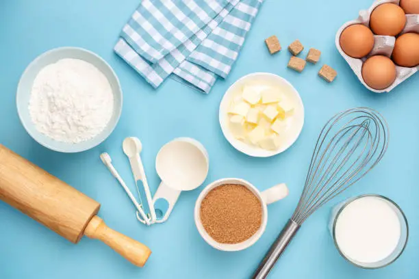 Photo of Kitchen utensils and baking ingredients on blue background