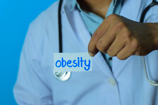 Doctor holding a card with text obesity. Medical and healthcare concept.