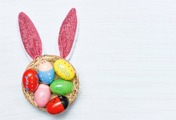 istock Colorful easter eggs and easter bunny ear rabbit in basket nest 1135045188