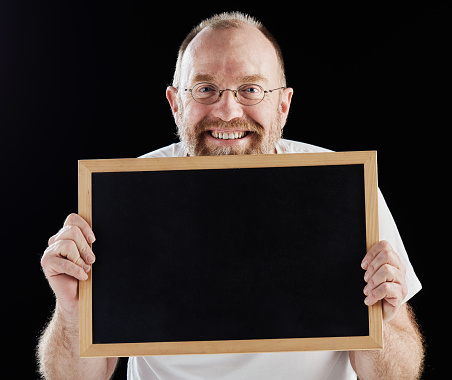 Smiling mature man holding up blank chalkboard