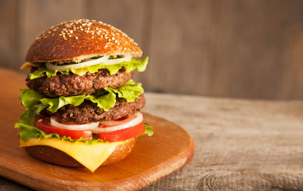 istock Tasty burger with cheese on wooden table 1135050242