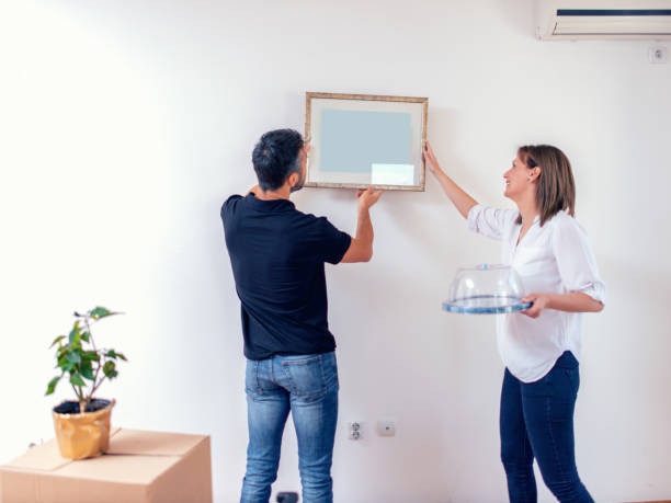 istock Couple hanging picture with frame on wall 1135050579