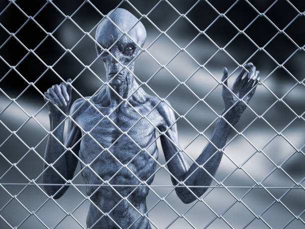 3D rendering of an alien creature standing trapped behind a chain link wire steel metal fence, looking at you.