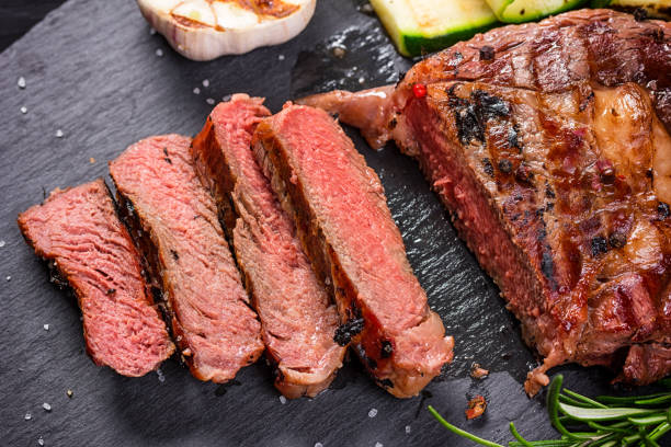istock Juicy medium rare beef steak slices on ceramic board with herbs spices and salt. 1135055813