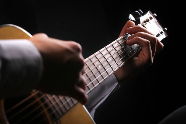 istock Young men playing the guitar with black background 1135059387