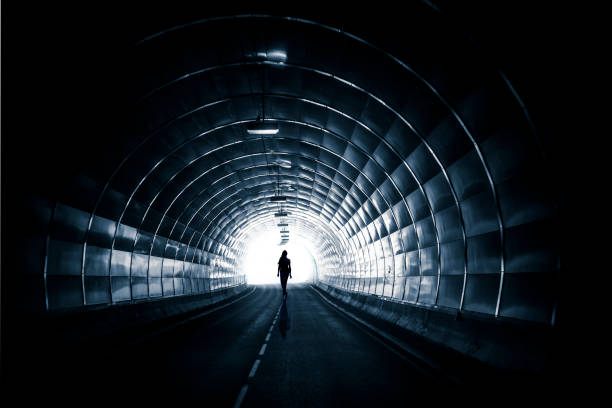 tunnel scuro con silhouette - luce alla fine del tunnel foto e immagini stock