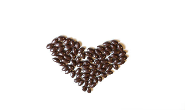 istock Nuts arranged in heart shape on background. Food image close up candy, chocolate milk, extra dark almond nuts. Love Texture on white grey table top view 1135060478