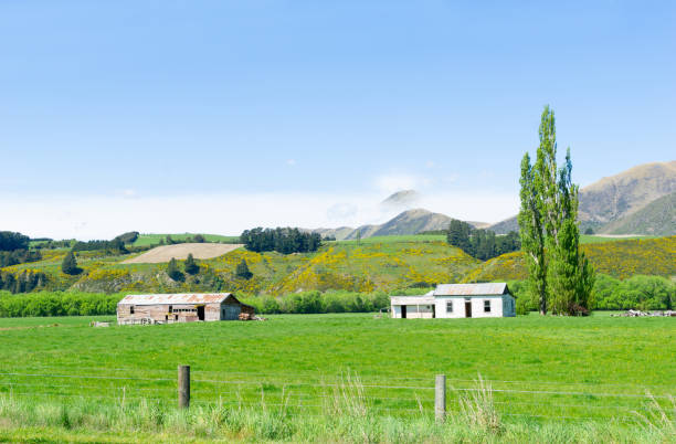 Rural land with fields and hills and old buildings under clear blue sky.