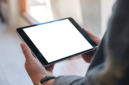 Imagen de maqueta de las manos de la mujer sosteniendo Tablet PC negro con pantalla en blanco horizontalmente en la cafetería photo