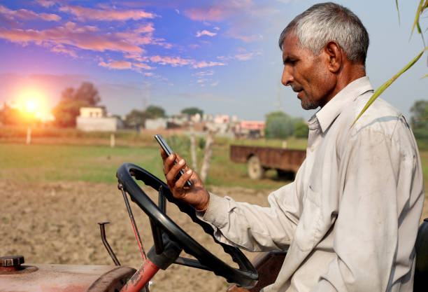 istock Farmer using phone while riding tractor outdoor in the field 1135064208