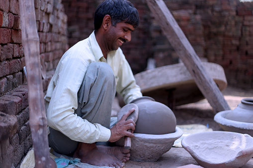 Potter molding a shape of mud pot at home.