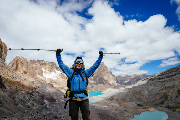 female mountaineer cheers on a 5000 meter high pass along the Huayhuash- Trek in the Peruvian Andess; Huayhuash Mountains stock photo