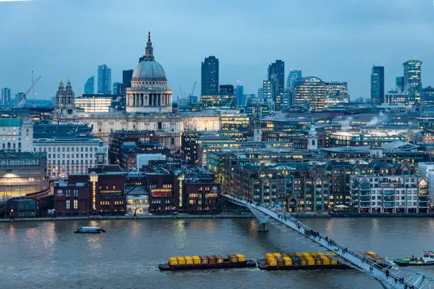 London city skyline with the iconic architecture of Saint Paul's Cathedral and its surroundings including: Millennium bridge, Thames river, Barbican buildings, illuminated during the blue hour. Shot with Canon EOS R full frame system.
