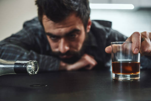 istock It is hard to understand addiction unless you have experienced it. Alcohol abuse: drunk man lying down on a table looking at empty bottle. Selective focus. Front view 1135071182