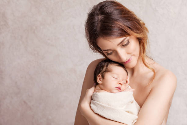 pretty young woman holding a newborn baby in her arms. portrait of mother and little baby. happy family concept. copy space - baby mother sleeping child imagens e fotografias de stock