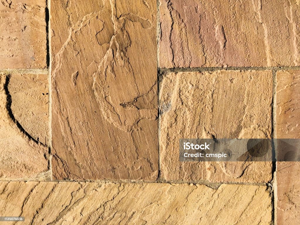 Background of sandstone tiled Sandstone flooring in direct sunlight giving golden color Patio Stock Photo