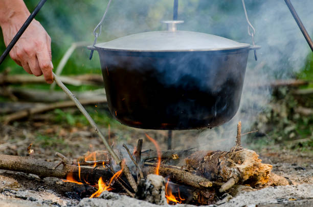 istock A man's hand kindles a fire under a pan, which stands on a fire. 1135076861