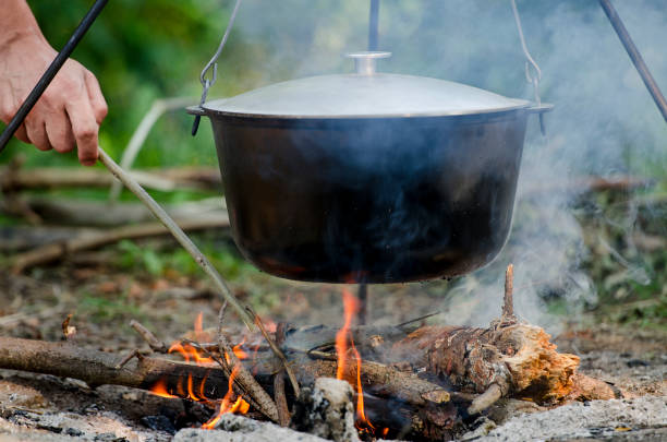 istock A man's hand kindles a fire under a pan, which stands on a fire. 1135076862