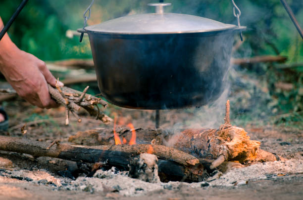 istock A man's hand kindles a fire under a pan, which stands on a fire. 1135076863