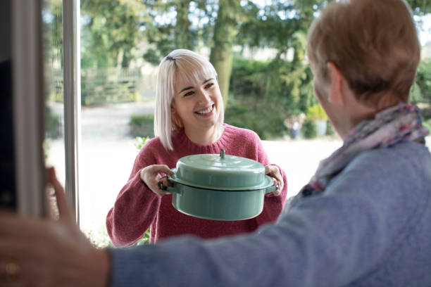 Woman Bringing Meal For Elderly Neighbour Woman Bringing Meal For Elderly Neighbour doing a favor stock pictures, royalty-free photos & images